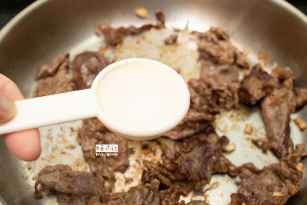 煎至肉色變深時，加入一大匙米酒，轉中大火開始拌炒。