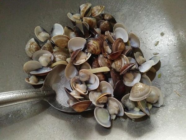 依序放入蛤蜊，轉至中小火（要注意蛤蜊肉不要炒太久，會過老的不好吃，且會縮小），並蓋上鍋蓋蒸熟，