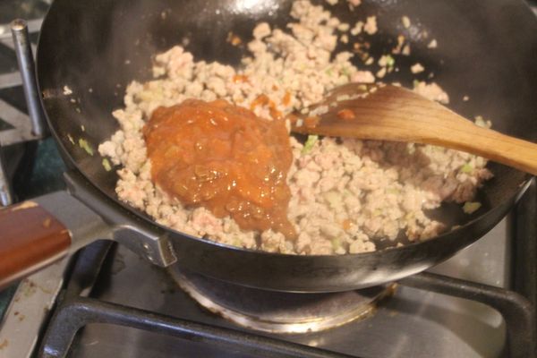 放入紹興酒、糖、蠔油和豆瓣醬，炒出香味。