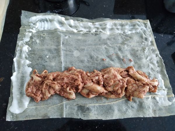 準備一張腐皮，包入適量内餡卷起，周圍用麵糊封口。