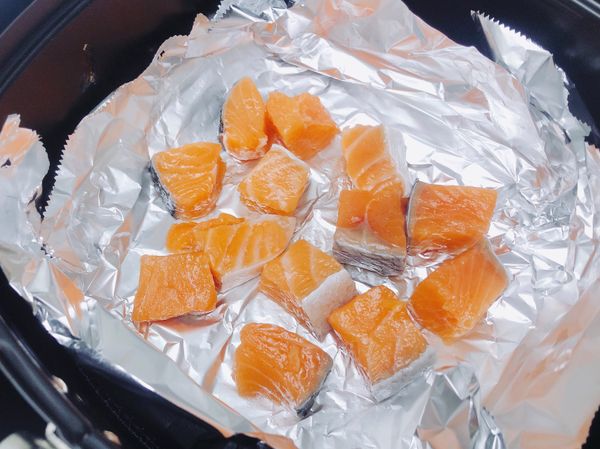 先舖一層鋁箔紙，放上切丁後的鮭魚（鮭魚丁可以用一些鹽巴調味）
設定氣炸鍋時間與溫度（8分鐘/180度）