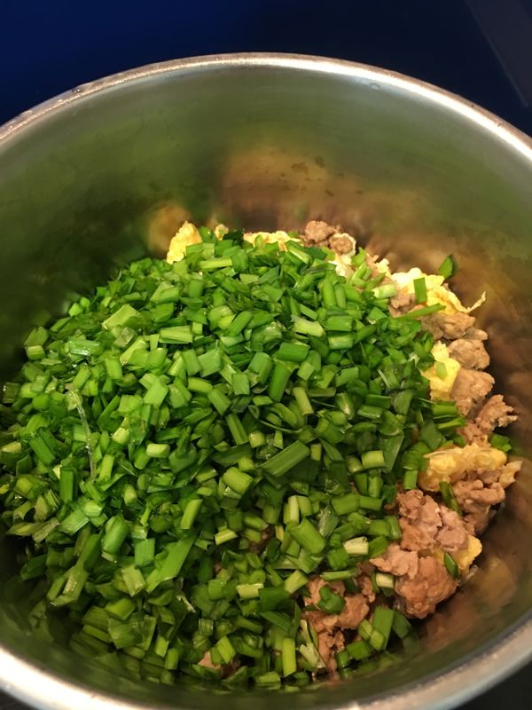 關火後, 等炒好的內餡稍涼, 將韭菜倒入攪拌.