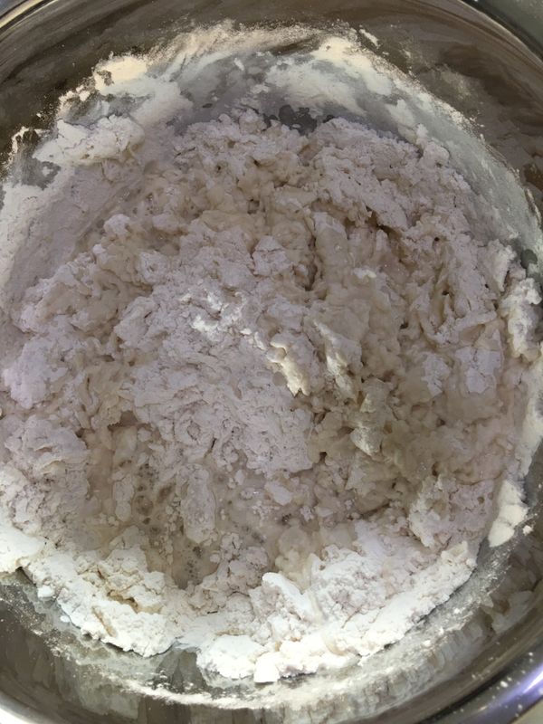 熱水倒進盆內的麵粉, 用筷子攪拌讓麵粉變成燙麵.  再將冷水倒入,  然後攪拌一下.