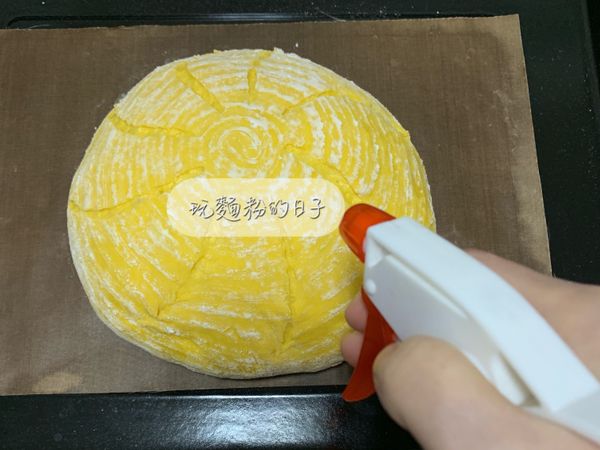 用麵包刀在麵團表面劃線，噴水器拿高點，讓水珠自然灑在麵團表面。