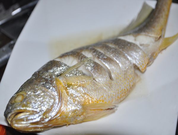 取出真空包裝整包泡入水中解凍，直接取出已去鱗.鰓.腸的黃魚，由兩面各劃數刀，鋪上薑片及放入蒸盤，加些米酒放入電鍋蒸熟備用