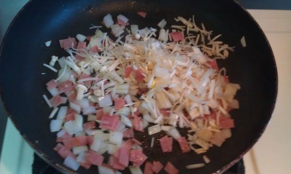 平底鍋加入一大匙油先炒香洋蔥和火腿後，加入金針菇炒軟(略出水)。