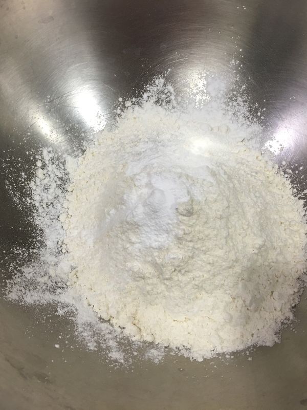 將低筋麵粉、泡打粉、細白砂糖與少許鹽巴放入大鋼盆內