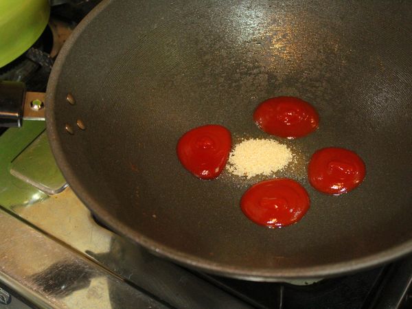 續原鍋, 留約一大匙油、加入番茄醬及砂糖, 小火炒至糖融化...