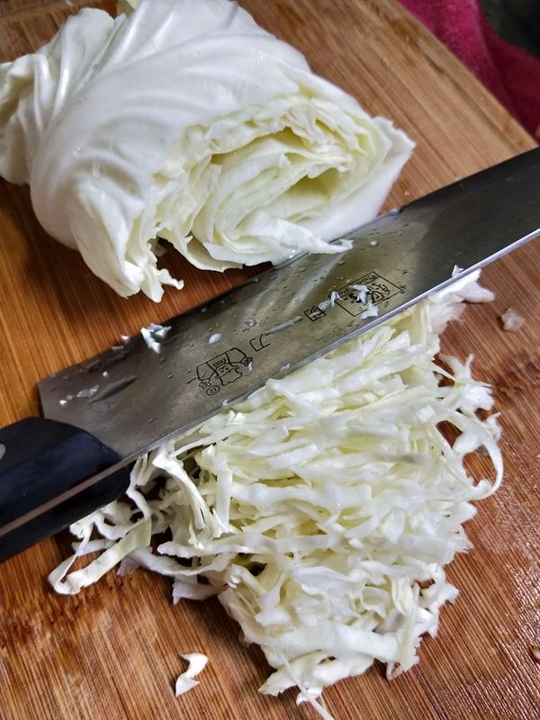 將一片一片的高麗菜葉洗淨後捲起切絲