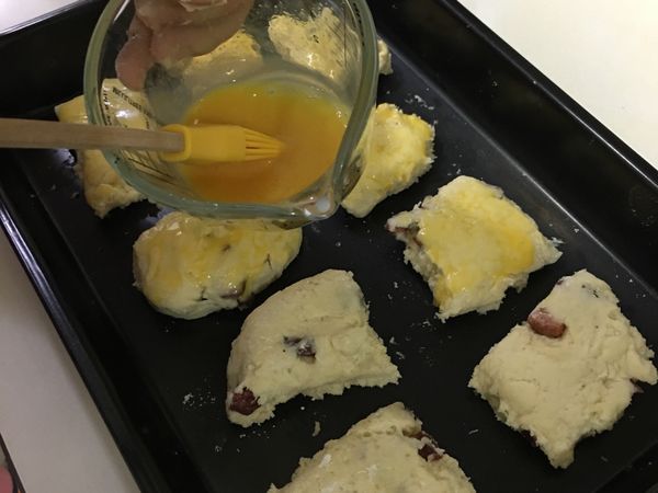 烤箱預熱至220度C，將分割好的司康麵團放魚烤盤上，並刷上蛋液