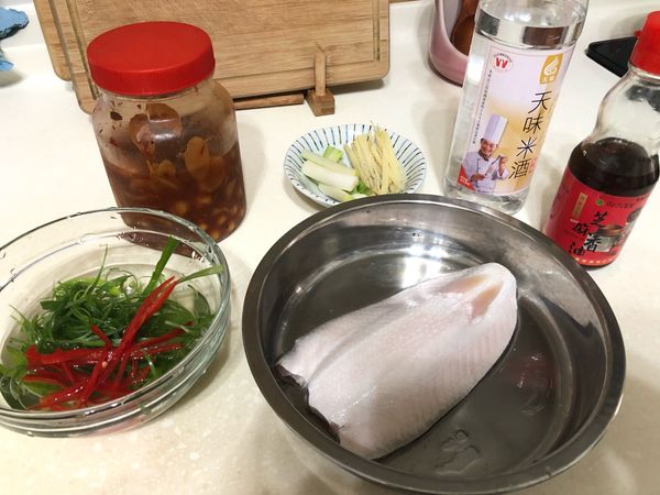 把蔥分成蔥白和蔥綠，蔥白的的部分切段，蔥綠切成絲，薑片也切成絲，辣椒去籽切成絲，虱目魚加上一大匙米酒醃製去腥