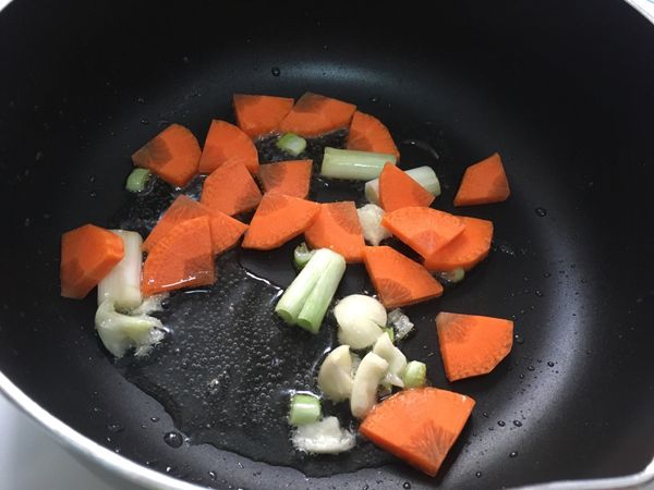 起鍋，下油，油熱後放入蔥白、蒜一起爆香，再加入紅蘿蔔拌炒。