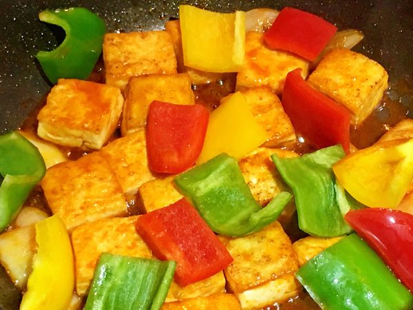 待半收汁後，放入紅黃青椒片拌炒至收汁熟透，起鍋前淋上太白粉水勾芡即可盛盤。