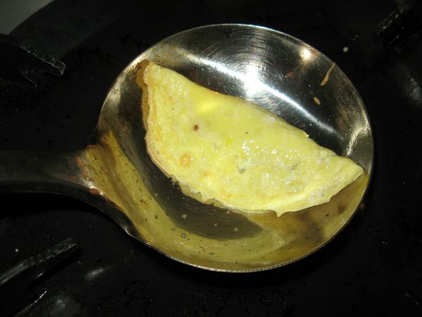 蛋皮中間部分，仍是半熟狀態‧在中央稍前處放入炒好的肉餡，將蛋皮
摺半對疊當作蓋子，把另一半黏住，煎成像餃子狀。