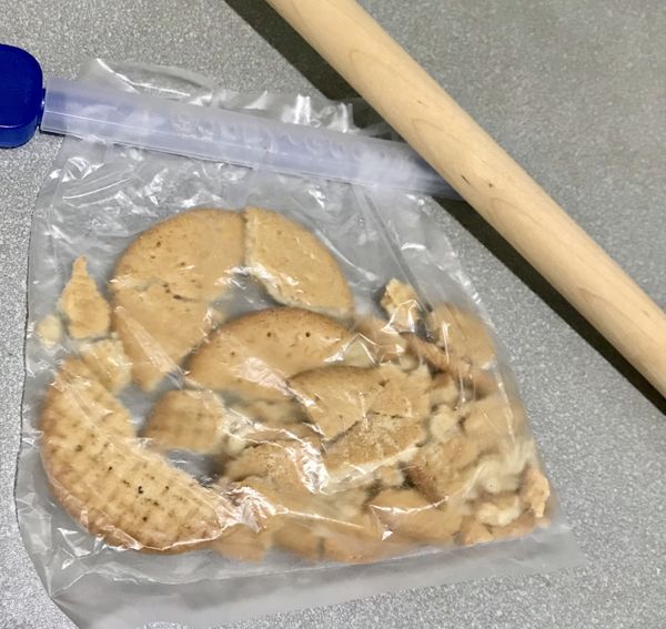 6格烤模用保鮮膜包2層，注意凹槽處用小杯子壓一壓，一行壓好再壓一行。將餅乾屑平均分成6份，緊壓在模底，放入冰箱冰30分鐘。