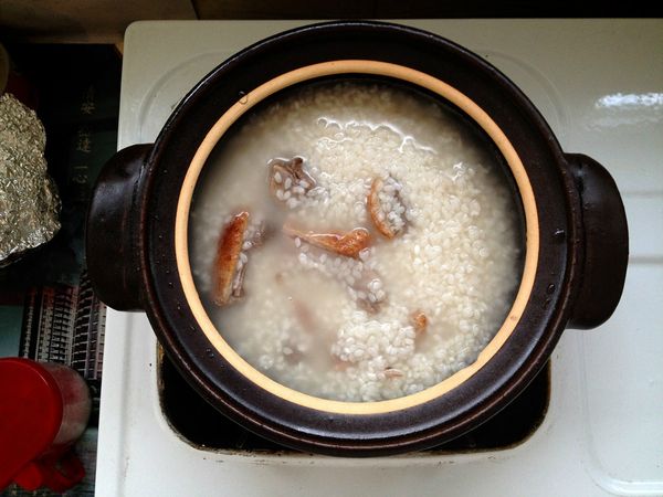 將米和鴨肉倒入已盛水的小土鍋中，蓋上鍋蓋，以中大火煮滾。