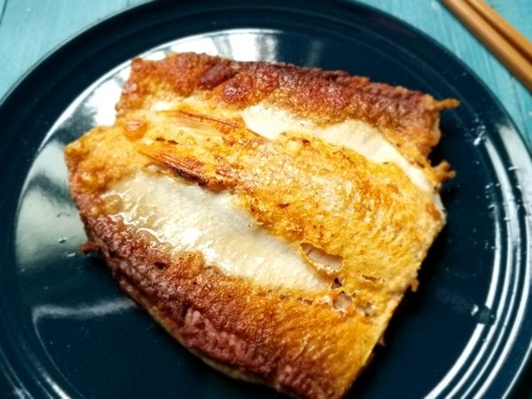 魚肚面煎到金黃時， 翻面(並打開鍋蓋}繼續煎魚皮3~5分至金黃酥脆， 並自20公分高處，用三根手指抓一搓鹽輕輕均勻灑在魚肚面。(鹽巴也可以改用胡椒鹽)

超簡單的【鹽味香煎虱目魚肚】上桌囉!