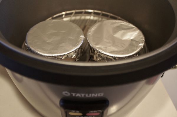 電鍋先放入蒸架後，再擺布丁模，倒入一杯水