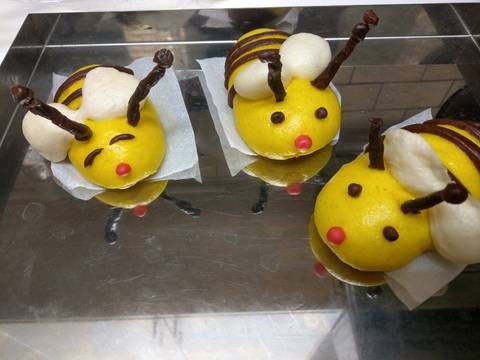 將可可麵糰壓成長條型,先再小蜜蜂身上擦上薄薄的開水,再將裁好的可可麵糰黏上去還有黏上觸角,另外搓兩個小圓球,黏上去當眼睛,取原色麵糰8克作蜜蜂翅膀,另取約1克紅色麵糰當小嘴巴,組合好後靜置後發30分鐘