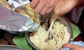 4、三種巧克力用菜刀切細末放入單柄鍋，再將單柄鍋放入大鍋隔水加熱，將巧克力煮至溶化(同時攪拌避免煮焦)，待巧克力成液狀時，熄火，依序加入花生拌勻再加入剪好的仙貝拌勻再加入適量的玉米脆片拌勻