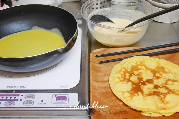 將可麗餅麵糊煎成可麗餅：平底鍋開小火，用紙巾沾一點油擦拭平底鍋。鍋溫熱後倒入1大匙麵糊，剛倒下就盡量搖勻，讓麵糊攤成圓形薄餅。