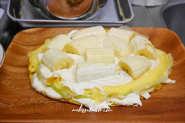 排好後壓上一層可麗餅，抹上卡士達鮮奶油，再排下一種水果。