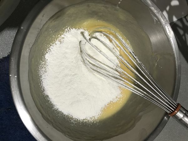 加入鮮奶，攪拌均勻後，分3次加入過篩的麵粉，用拌切輕壓的方式，直到看不到粉末。