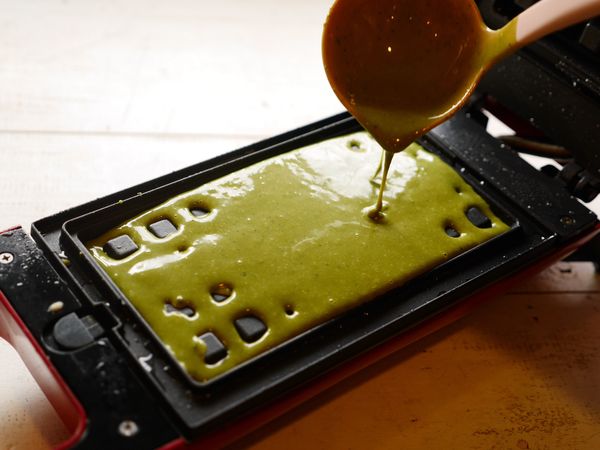 鬆餅機刷上些許植物油預熱，啟動開關，等待預熱完成綠燈亮起後，倒入約8分滿麵糊。。