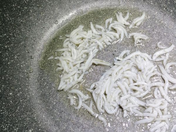 鍋裡放入一大匙油，爆香蒜末，再將小銀魚放入，小火輕輕拌炒幾下，迅速加入蛋液