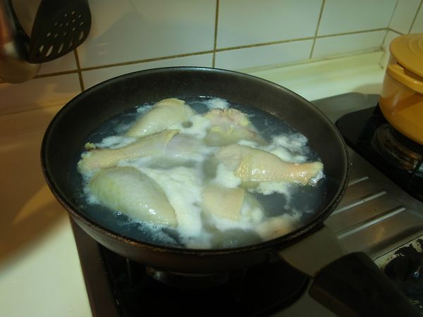 一個鍋子先煮水，放下雞腿和薑片去燙到浮沫、油都出來，把整鍋放到水龍頭底下去沖，洗淨雞腿後拿起來