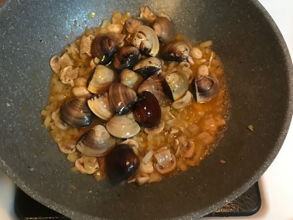 步驟4撈起蝦子的原鍋繼續放入洋蔥炒香，接著放入蘑菇拌炒，最後倒入蛤蜊與4大匙的煮麵水後，蓋上鍋蓋悶煮蛤蜊2至3分鐘，待蛤蜊打開後，將其撈起放置一旁備用