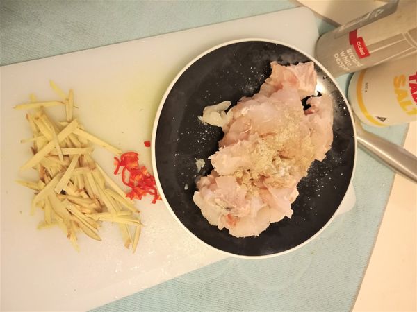 魚肉切塊，容易入口的大小，加20克胡椒、少量鹽巴抓醃。
薑切絲、辣椒去籽切絲。