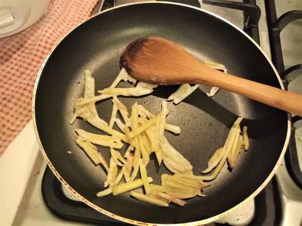 開大火熱鍋，加入葵花油和薑絲，用鍋鏟拌炒直到薑的香味飄出。