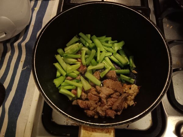 倒入牛肉絲、芥藍菜梗，拌炒至肉絲半熟。