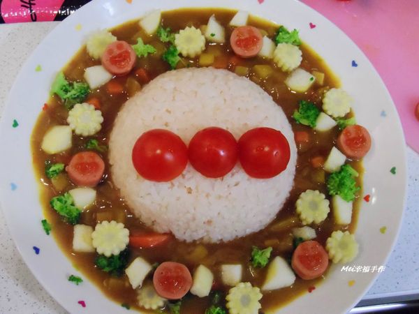 步驟3在飯的週圍放上咖哩，燙熟的玉米筍片，花椰菜，蘋果丁和小熱狗