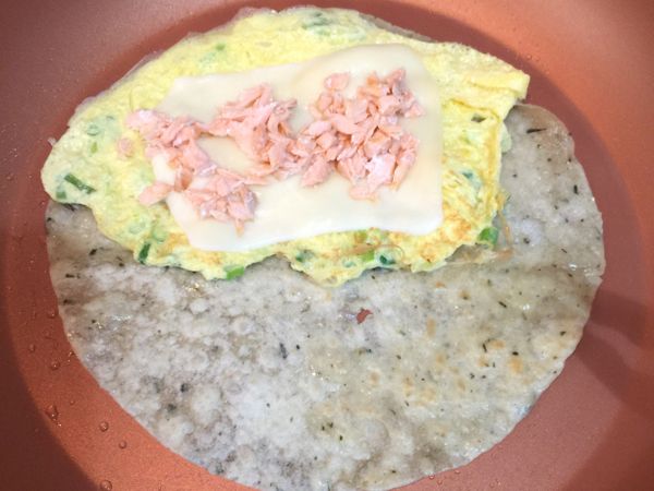 小火熱鍋，放入蛋餅皮，兩面煎一下，將餅皮對摺靠鍋的一半；在另一半鍋內加一點油，油熱倒入蔥蛋液並用筷子順時針方向攪拌鍋中蛋液使其鬆軟，在蛋完全凝結前將剛剛摺起的餅皮蓋回去，輕壓使餅皮與蛋黏合，在翻面（不要煎太久蛋會老掉）。等蛋熟的時間將鮭魚末放鍋邊稍微回溫。
翻面後關火，放上起司、鮭魚末，捲起完成。