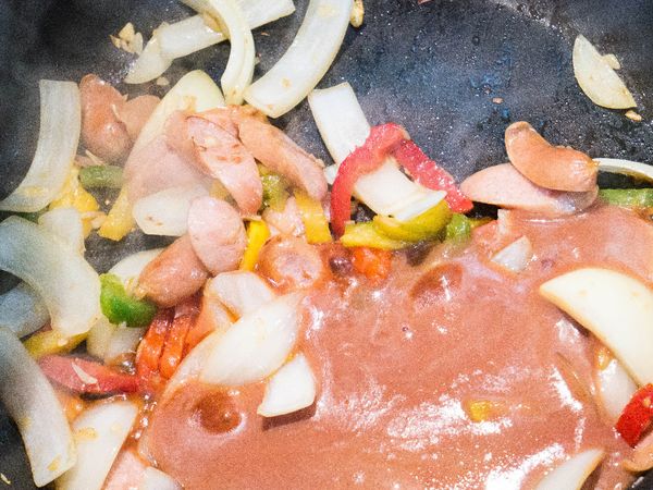 在鍋中倒入橄欖油並放入蒜片，小火煎出香味。
香味散出後，加入青椒、洋蔥及鑫鑫腸中火翻炒。
接著加入醬汁燉煮。
