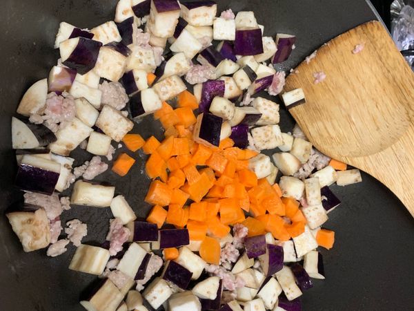 分別放入茄子和紅蘿蔔拌炒，加入水蓋鍋悶燒約2-3分鐘