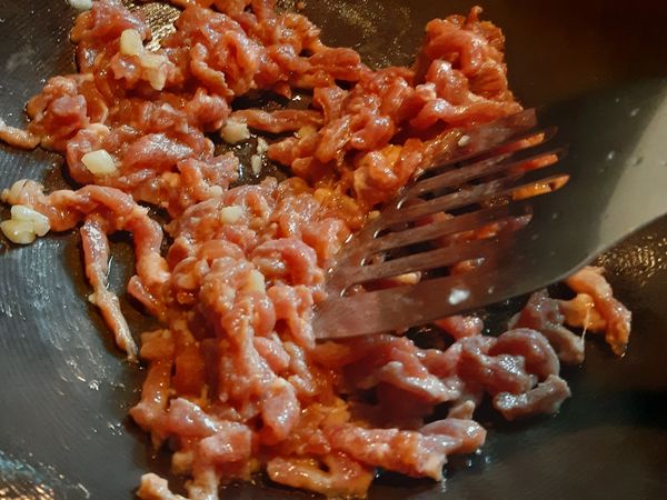 熱鍋放1/2大匙冷油，隨即將肉絲放入以中小火快速炒散，推到鍋邊。