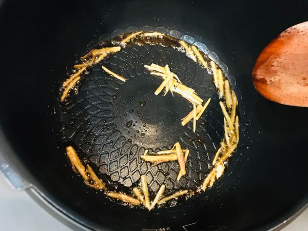 萬用鍋選擇「烤雞」模式，按下「開始烹調」後合蓋，待加熱完全發出提示聲開蓋，倒入麻油一大匙及薑絲爆香。