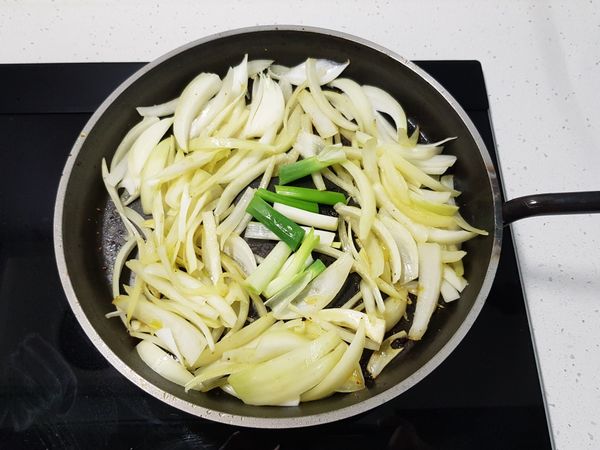 加入洋蔥絲、蔥白，以小火慢慢炒香。