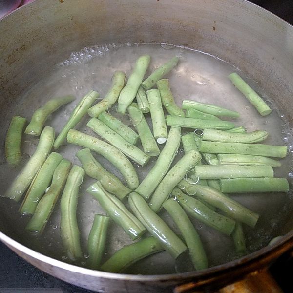 煮鍋熱開水，將切成段的四季豆下鍋川燙到熟透後撈起。
