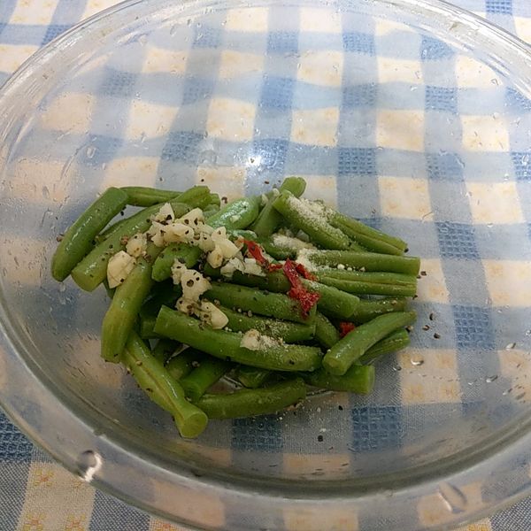 取去一深碗將泡涼的四季豆濿乾水份放入碗中接著把蒜末、黑胡椒粒、紅辣椒絲、雞粉、香油和四季豆拌勻就完成了。