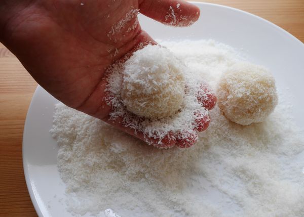 把剩餘的1杯椰子粉倒在盤子上，將椰子球表面沾上椰子粉。