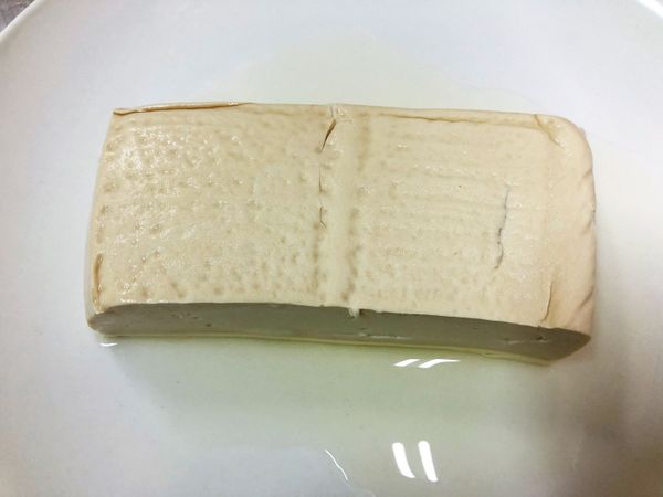 這道菜可以選擇板豆腐/傳統手工豆腐來做，嫩豆腐我覺得比較不適合。
豆腐使用前可以用盤子放在上面壓著，大約壓半小時讓豆腐出水。
出水後把豆腐切成厚片狀。
(照片中唯一塊豆腐，這次料理用量為兩塊)