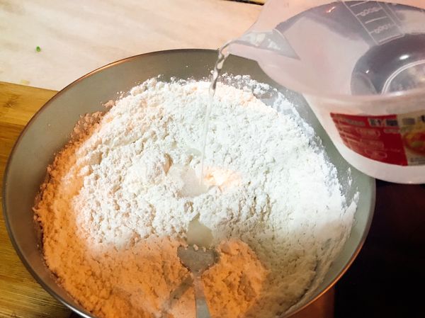 低和高筋麵粉混合後，分次慢慢加入溫熱鹽水。用叉子拌勻，漸漸揉成團。