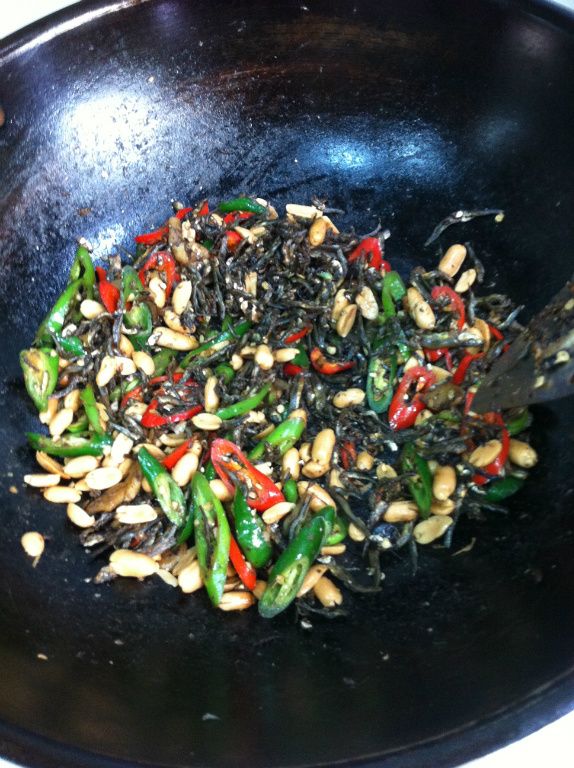 關火將蒜味花生拌入小魚乾。