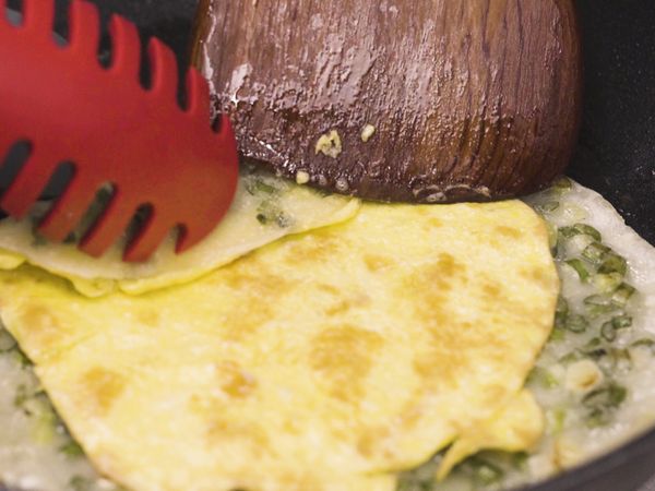 原鍋下油，倒入蛋液、再蓋上餅皮，待餅皮與蛋黏合在一起即可翻面，並由一端捲起並切小段就完成囉～