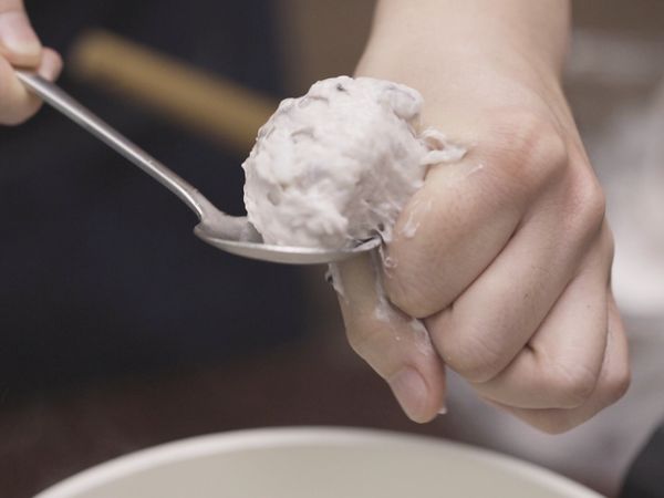 準備一鍋熱水，拿取些許混合好的花枝漿，用手的虎口擠出圓球，再用湯匙沾水後刮起放入鍋中。