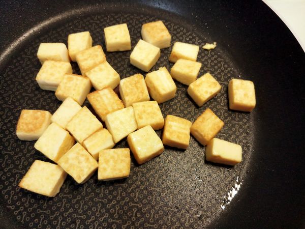 續鍋倒適量油將雞蛋豆腐丁拌炒煎至表面金黃色